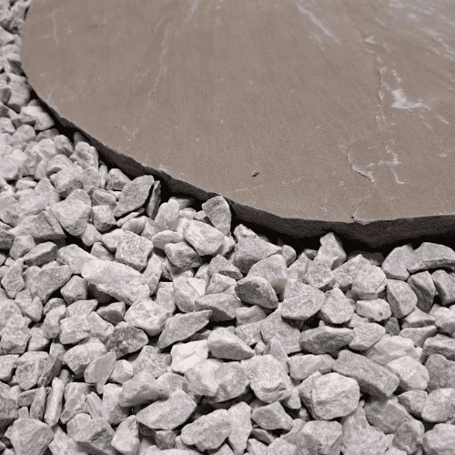 Close-up van een halfronde zandsteen flagstone met gladde oppervlakte, direct naast een verzameling hoekige, witte grindstenen, waarbij de textuur en vormen een natuurlijk contrast vormen